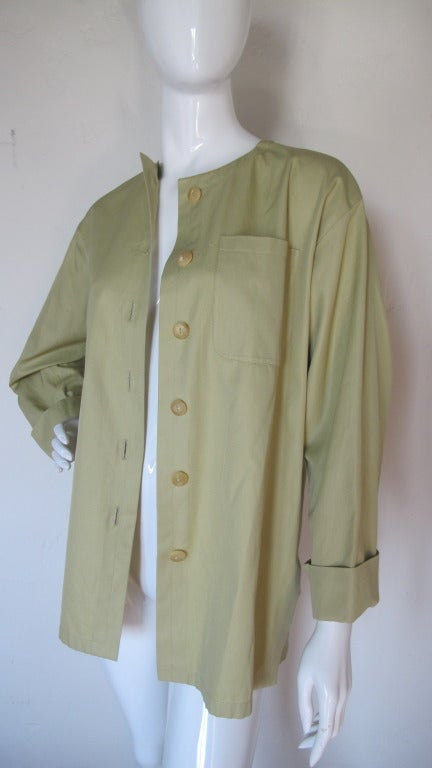 1990s Yves Saint Laurent 100% cotton pale sage green button down top that can be worn either alone or as a jacket. The top is chic and understated with details such as bottom side slits, cuffed sleeves, textured buttons and a single front pocket.