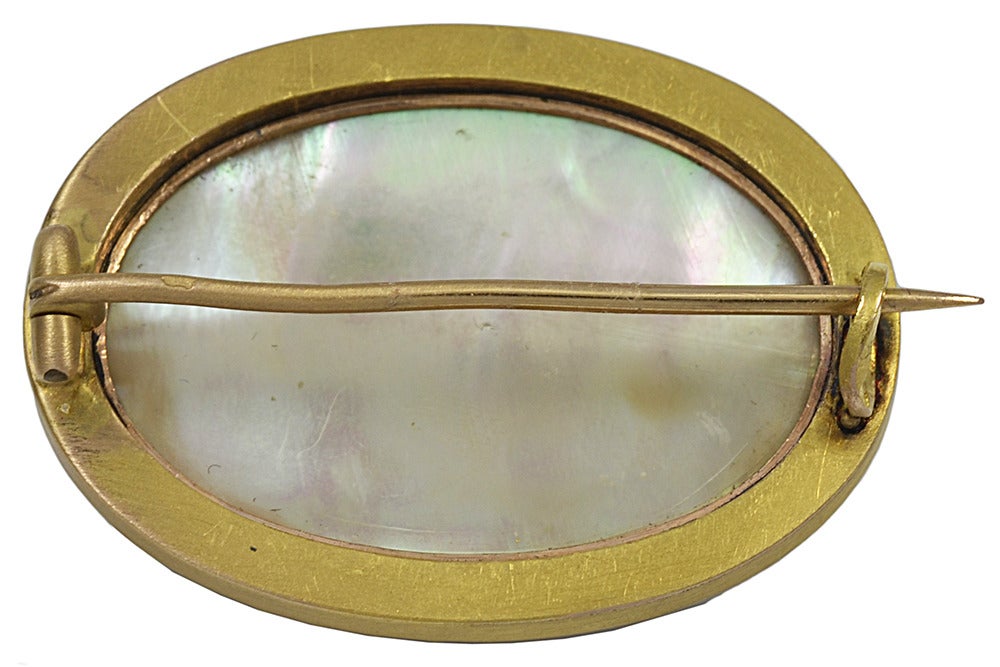 Of oval shape with the figure of a little winged girl ( angel?), walking barefoot through the snow with her hands in a fur muff! 
The frame decorated with gold wire work and the reverse with a backing of Mother of Pearl .There are French gold marks