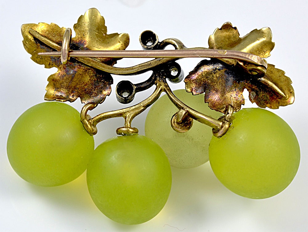 The remaining four succulent grapes hang down and the stems where three have been eaten are capped with diamonds. A masterpiece in jewelry design.

Two well modeled Gold vine leaves complete the piece and on the reverse are French 18 kt. Gold