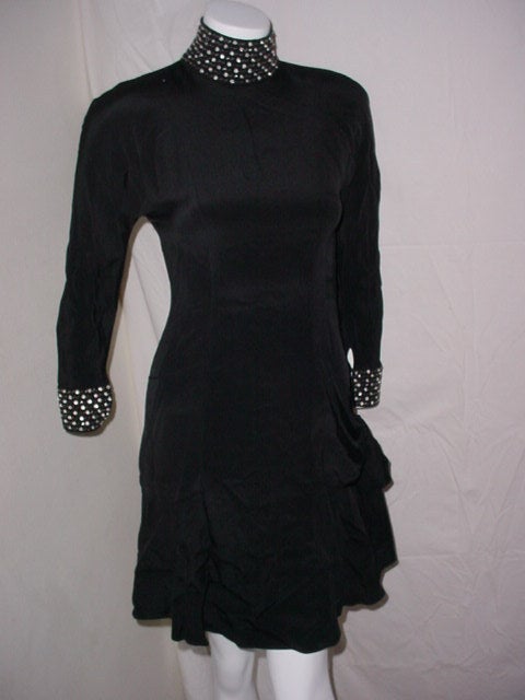 Vintage 80s dress by Paris designer Bernard Perris. Black stretch fabric with lycra. Rhinestone jewel collar and cuffs. Excellent condition. Side zipper. Draped side swag. Size Small.

34 inch bust
24 inch waist
38 inches long