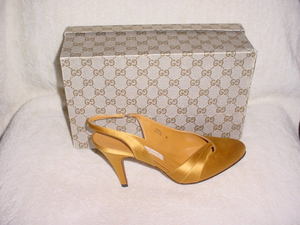 Vintage gold satin Gucci shoes from the 70s. Unworn with box. Right shoe is size 37.5 M and left is size 38 M. Heel of 3.5 inches.