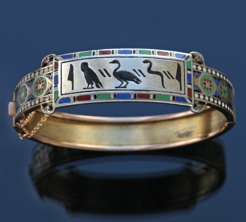 Remarkably fine eclectic bangle of early Egyptian & Gothic revival design.
H  1.60 cm (0.63 in)    W  6.80 cm (2.68 in)
Origin: France, c. 1878
Marks: Maker's mark partly obscured.
Case: Fitted Case
Condition: Good, with minor enamel repair. Wear