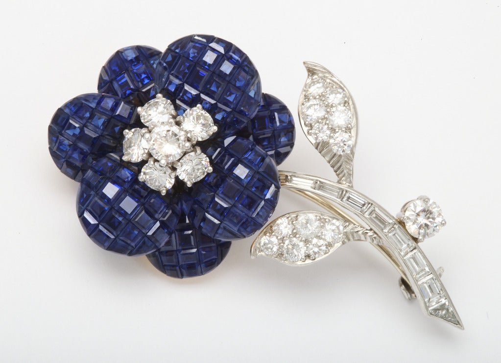This Magnificent flower brooch by Van Cleef and Arpels is truly one of a kind. The Sapphires are meticulously set invisibly and is accompanied by round brilliant cut diamond cluster stamen and baguette-cut diamond stem. The leaves are pavé-set