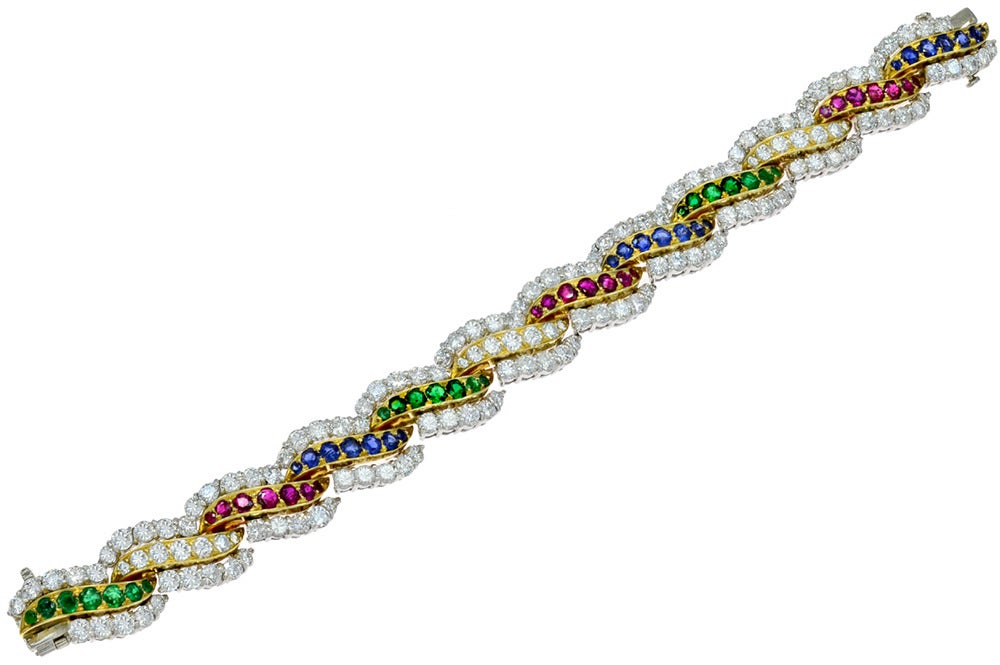 A dazzling Van Cleef & Arpels Platinum, Gold, Diamond and Gem-Set bracelet. This bracelet is stylized in alternating gold ribbons containing round diamonds, Rubies, Emeralds and Sapphires. This bracelet contains approximately 13 carats of diamonds.