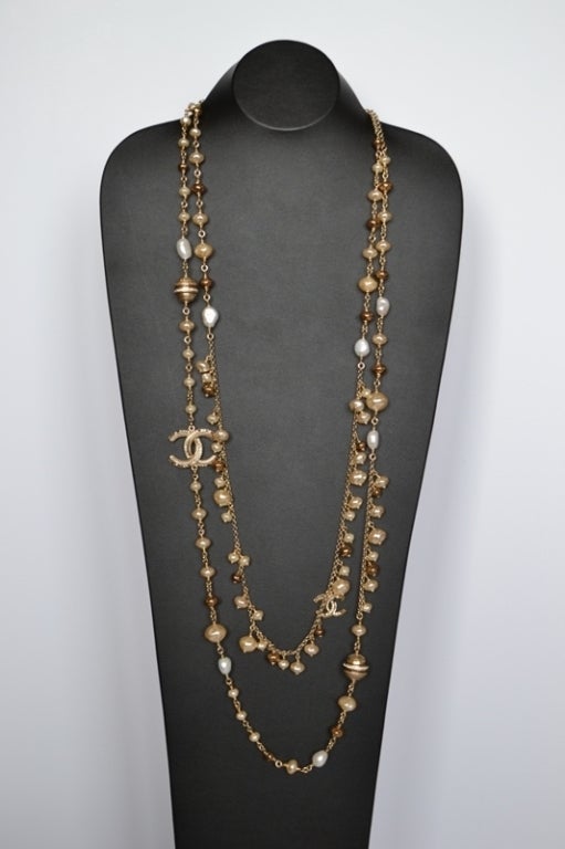 Chanel necklace Strass Balls 
Costume Pearls 
Golden Stainless steel chain 
CC plate with Swarovski strass
Amber and white tones
2 rows
Pristine condition Never worn 
Dimensions : 45 inches 
It will come with a velvet pouch

All ours items