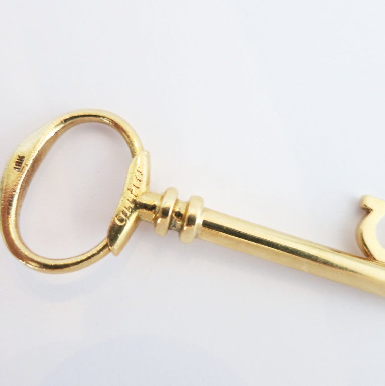 Charming eighteen-karat gold key ring in the form of a skeleton key.  Sprung top lifts and swivels to add key.  Signed Cartier, numbered.  Would also be lovely worn as a pendant.