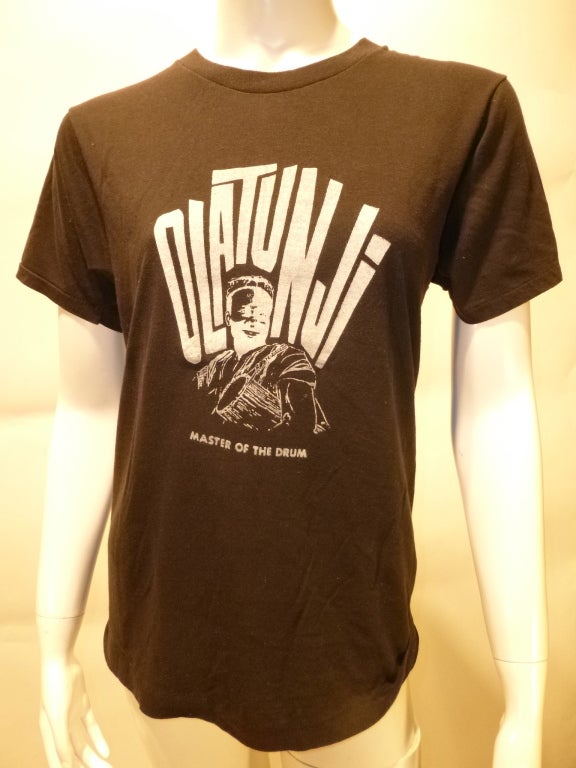 Babatunde Olatunji was a Nigerian-born drum virtuoso who released many records and performed on a myriad of others' records and in live collaborations. Olatunji's 1984 LP 'Master Of The Drum' is rare indeed. This is a promotional T-shirt for that