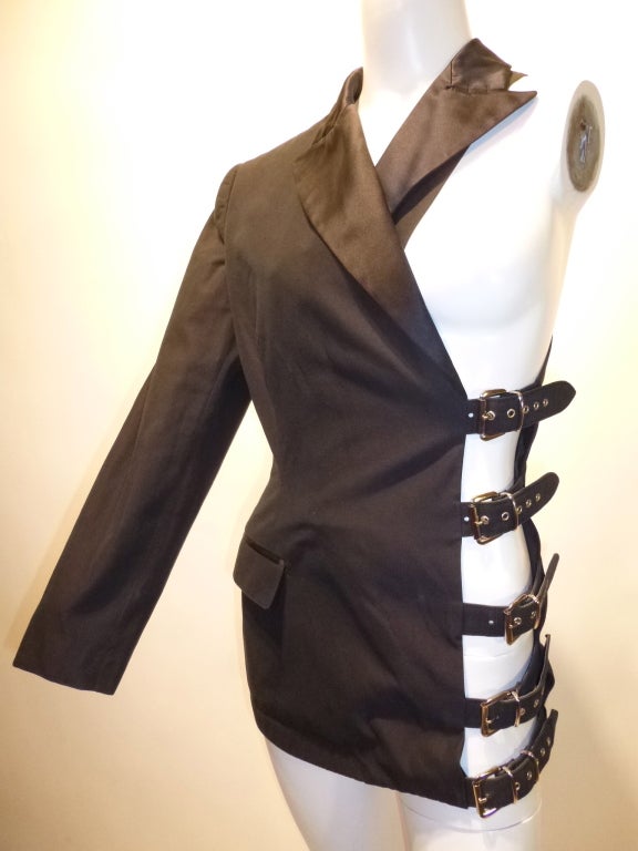 This is a rare, iconic JPG bondage-inspired tuxedo jacket with an entire side cut away, replaced with big straps and buckles, with relatively traditional detailing elsewhere. Faux front pocket, 5 buckled straps on the side. Gorgeous vintage
