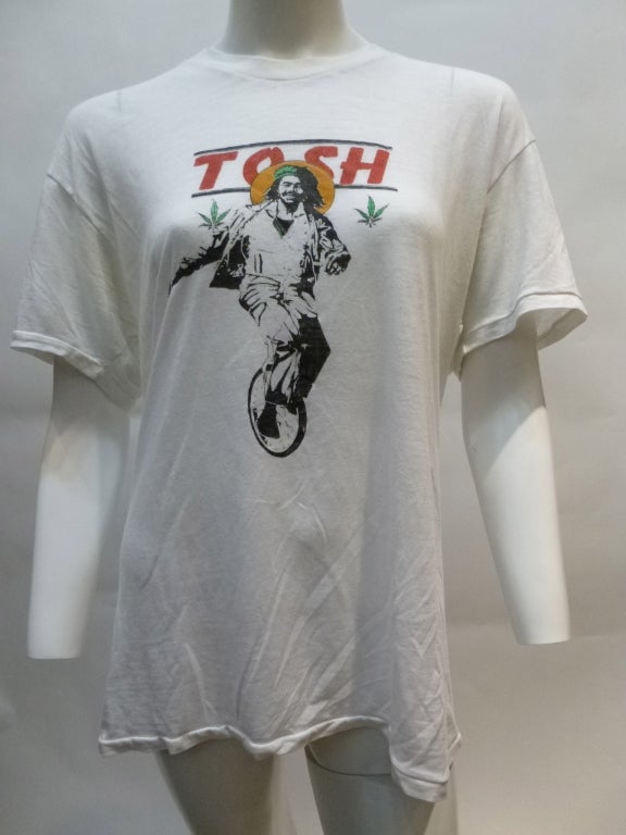 This is a promotional t-shirt for Jamaica artist Peter Tosh. He was very often seen on a unicycle during his solo career, and this shirt is a drawing of a photo where he is holding a copy of his 1979 LP Mystic Man, so we're going to date this shirt