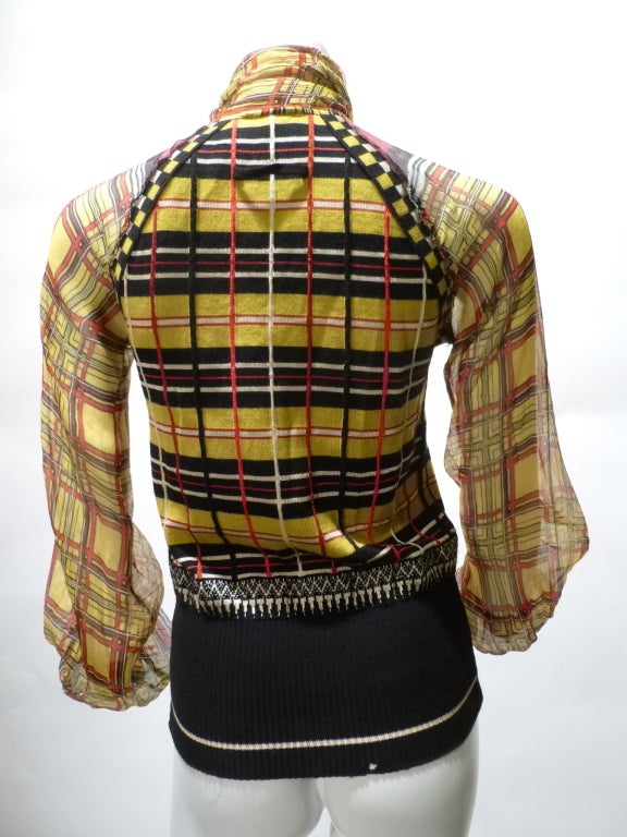 Gorgeous Jean Paul Gaultier Maille Femme pullover blouse in wool, silk and rayon in a funky plaid. There's a button closure behind the attached pleated bow. The arms and shoulders are sheer. There is a very small moth hole in the waistband in the