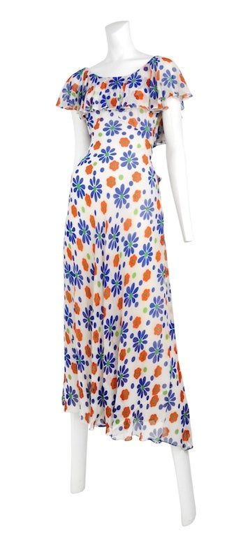 White chiffon daisy print dress with ruffle neckline and cap sleeves. Zip side closure with waist tie.