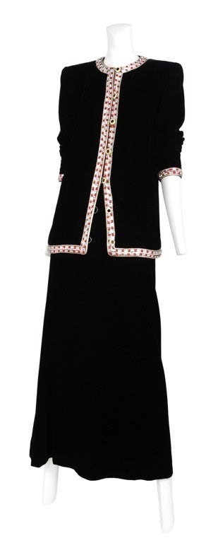 Black velvet high waisted column maxi skirt with long sleeve velvet jacket. Jacket has sharp structured shoulders and front placket and neckline open is encrusted with gem and rhinestones.
