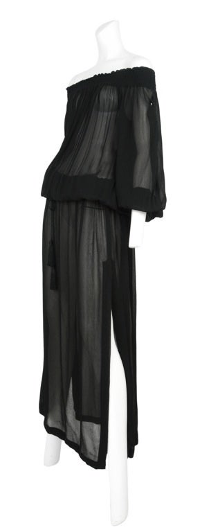 Black sheer crepe gown with off the shoulder elastic ruching detail, tassel detailed cinched waist and balloon sleeves with elastic cuffs.
