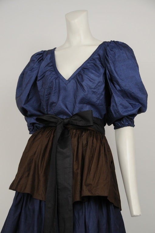 Silk taffeta color block 2pc.  Skirt is 3 tiered with alternating colors and large black bow sash. Navy blue blouse with banded v-neck and short poet sleeves.