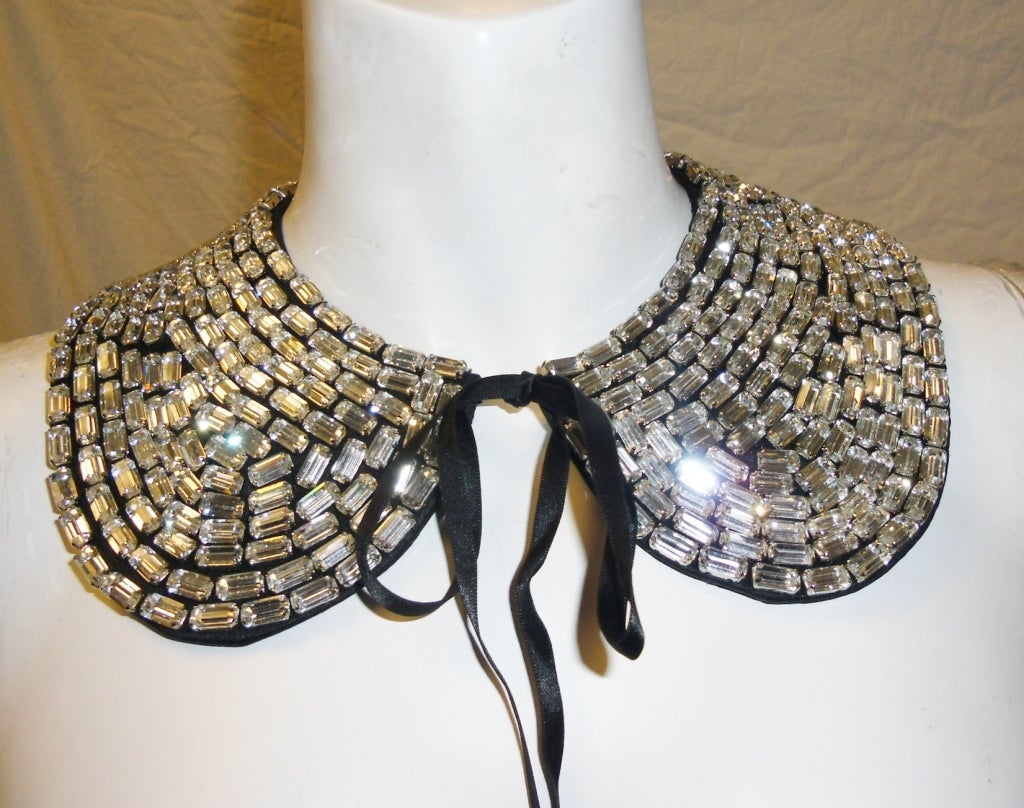 The crystal collar necklace is by itself a work of art, composed of dozens of hand sewn crystal baguettes resting atop a black double-faced satin collar. When tied over a simple tee shirt, or paired with a strapless evening dress, the result is a