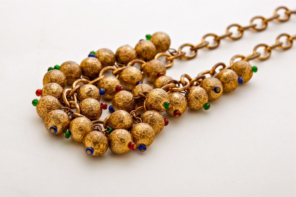 A Fabulous 1930's demi parure comprising a brass chain necklace with a festoon of textured gilt brass balls, each studded with a gem colored art glass bead and paired with a matching bracelet.

Necklace length : 15.5