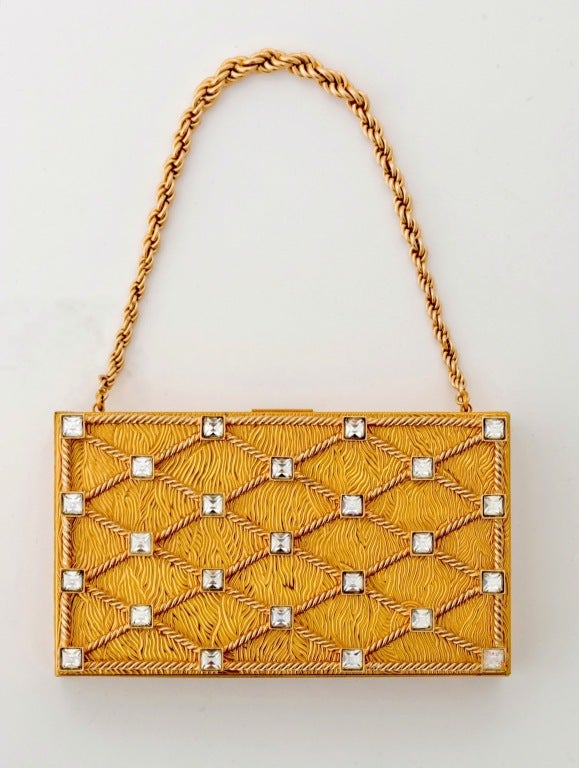 Stunning Evening Minaudiere of Etched Gilt Metal and Studded Rhinestones with a Gold Tone Chain.  A true sparkling wonder of vintage chic that is not only a jewel box but a substantial bag as well. 

Minaudiere's are ornamental cases for women's