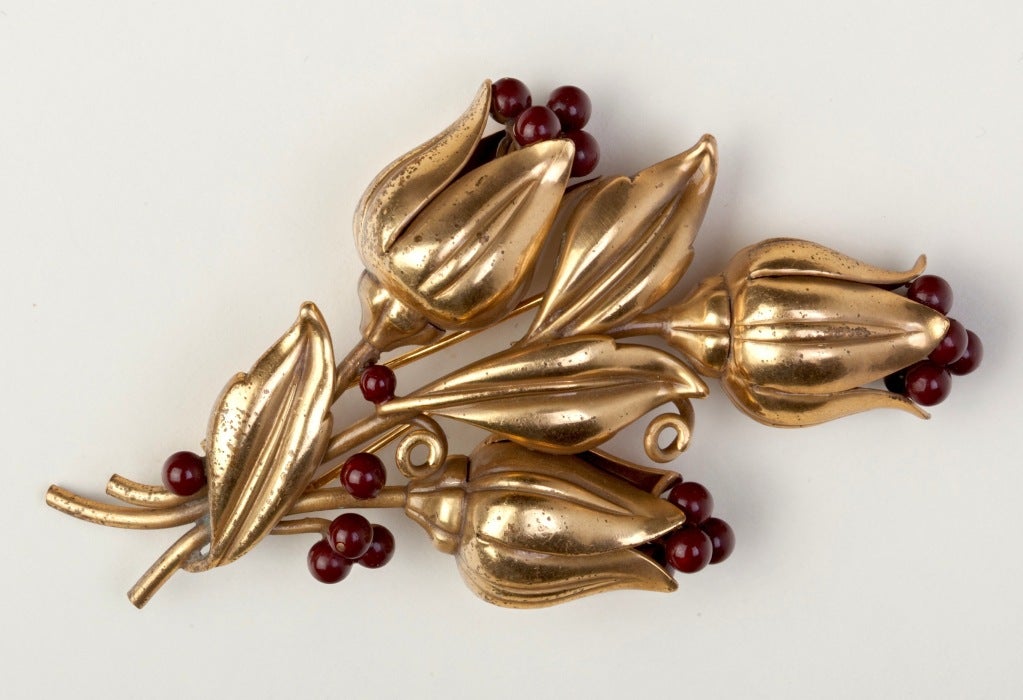 Extraordinary and rare Trifari fur clip in gilt metal with maroon enamel berries on a stem of flowers. The brooch is designed to be worn with the flowers pointed downward but could also be worn in various other directions. Stunning piece!