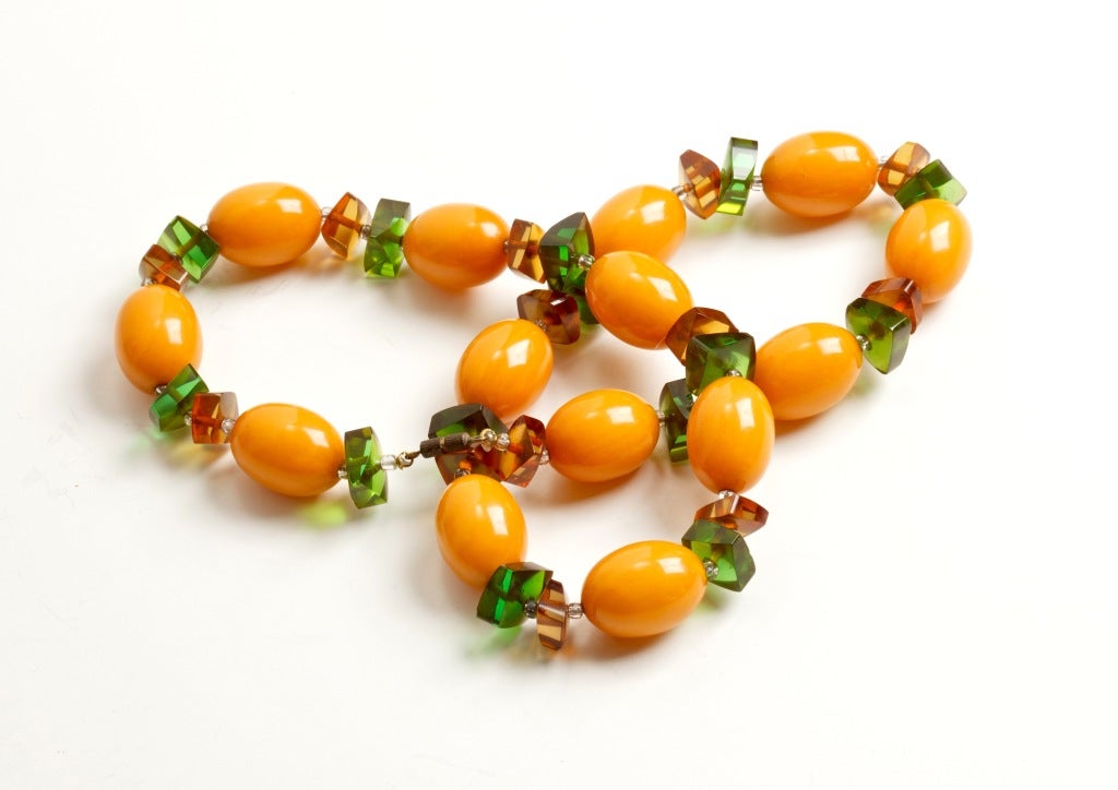 A wonderfully juicy beaded Bakelite necklace with large yellow Bakelite beads interspersed with green and brown geometric-cut Lucite spacers. Unsigned.