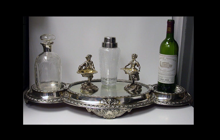 Fine Elkington & Company antique silver plate centerpiece mirror plateau bottle stand, England, 1869. The elongated three section centerpiece on four large turned supports, the central section with oval mirror plateau flanked on either side with