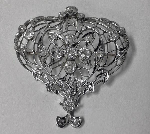 Edwardian Diamond Platinum Brooch, English C.1900. The brooch of heart shape, open pierced foliate design, diamonds milligrain set. The brooch centering four old cushion cut diamonds, approximately 1.50ct, calculated by formula, approximately SI