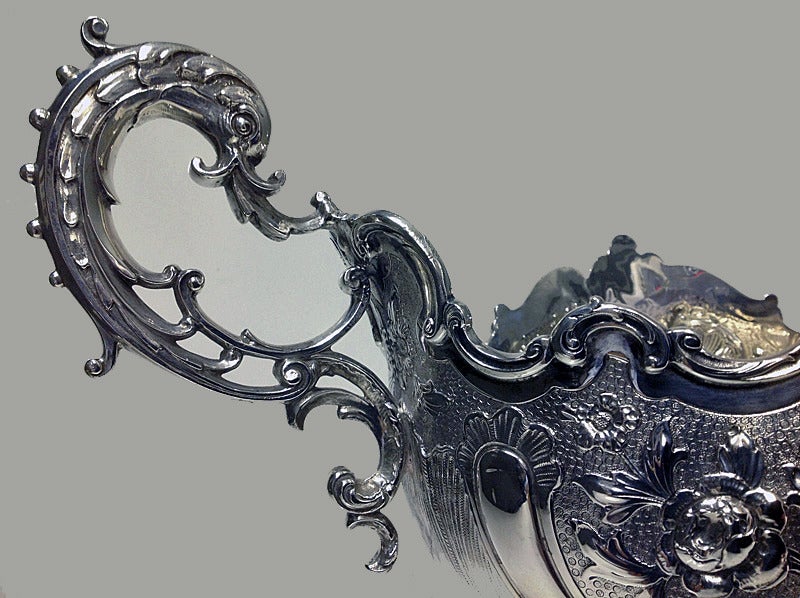 Fine Antique Victorian English Silver Centrepiece, London 1900, Barnard. The centrepiece of oval shaped form with embossed chased scroll and stippled decoration centering vacant cartouche on either side, the handles in the form of dolphins, the base