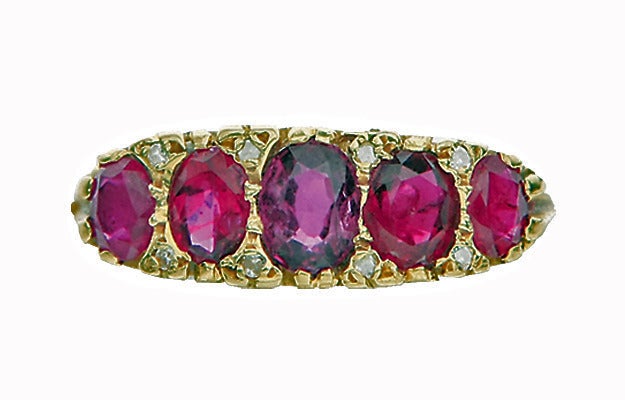 Antique Victorian five stone half hoop Ruby and Diamond 18K Ring, C.1900. The Ring comprising of five graduated oval facetted Purple Red Rubies, weighing a total of approximately 3.00 ct. accented at each corner with a small rose cut diamond. The