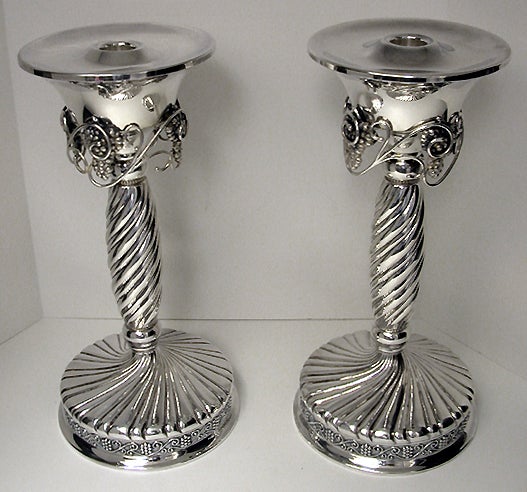 Pair of large Jensen style Sterling Silver Candlesticks. Each on spiral fluted swirl circular base with a frieze border of grape and foliate motif against stippled background. The slightly tapered bulbous stems with bead accented ovoid knops above