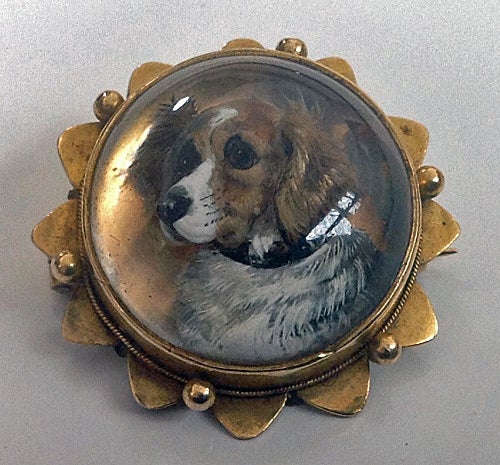 Antique English reverse intaglio crystal dog brooch, C.1880. The 15K brooch of circular shape with star gold border, the crystal painting of a spaniel. Locket to reverse. Diameter: 1 inch.  Total Item Weight: 8.3 gm.