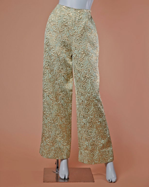 Stunning metallic brocade two piece dress and pants set by Ceil Chapman. This ensemble can be worn separately or together as a set. Pants are slightly flared at the bottom and feature a back zip closure. Dress has decorative matching buttons up the