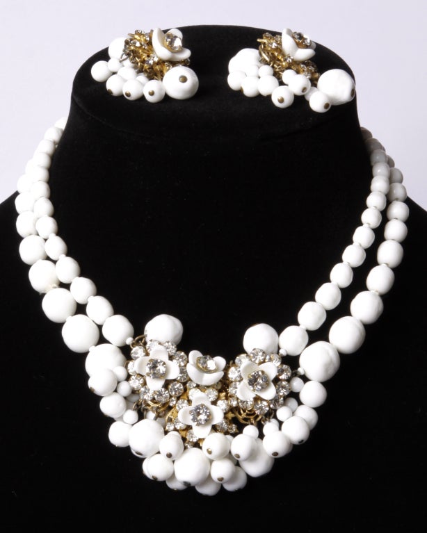 Highly collectible Miriam Haskell milk glass and rhinestone necklace and clip earring set. Signed gilt metal items feature Swarovski crystals with milk glass flowers and beading. Original clip backs intact. Necklace is approx 16
