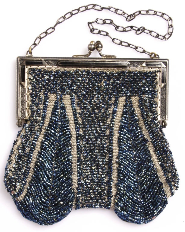 From the Suzanne Mounts Collection:

This is a magnificent and exceptionally beautiful vintage 1920s handbag, made of blue iridescent glass beads and metal links. The top is dominated by a beautiful silver-plated and black-enameled frame. The