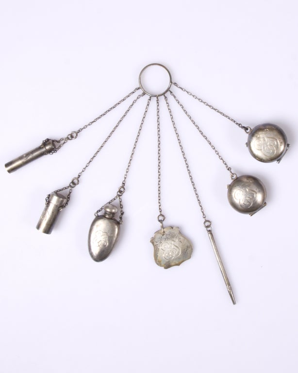From the Suzanne Mounts Collection:

Extraordinary example of a Victorian chatelaine. A chatelaine is a decorative belt hook or clasp worn at the waist with a group of chains suspended from it. Each chain is mounted with a useful household