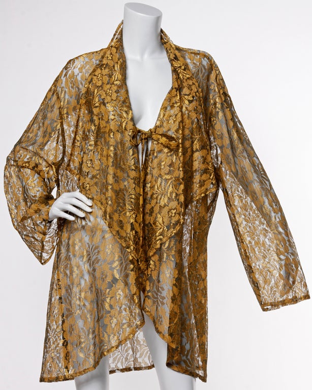 Metallic bronze sheer lace duster jacket by Mary McFadden! This jacket features an oversized, slouchy fit that would look great on smaller sizes as well as large. The jacket folds over and ties in the front and can be worn open or closed.