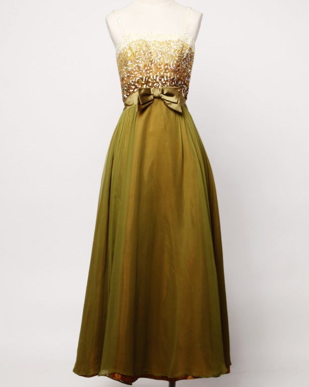 Olive green silk chiffon formal gown with an iridescent ombre sequin bodice that goes from dark brown to pale cream. Olive satin waistband with front bow detail. Sequin encrusted spaghetti straps and rear metal zip and hook closure.

The marked
