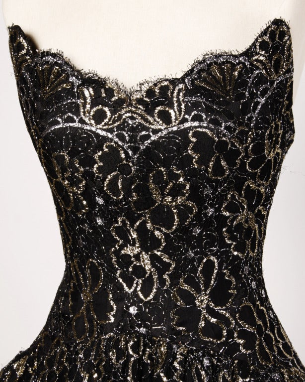 Gorgeous black lace strapless dress with gold and silver accents by Arnold Scaasi. Built in tulle crinoline and scalloped edges. Rear zip closure. Fully lined.