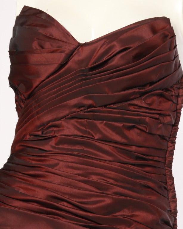 Phenomenal iridescent burgundy taffeta mini dress with asymmetrical ruching by Victor Costa. Strapless and body hugging with draping in all the right places. This dress features side zip closure and is fully lined.