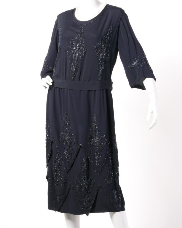 Amazing and completely convertible! This ink blue flapper dress can be worn with or without the 3/4 length sleeves. The sleeveless dress is done in a medium weight crepe fabric that is in amazing condition for its age. The hand beading is all in