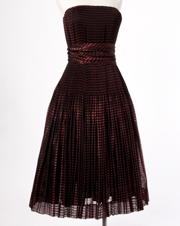 Phenomenal two-piece set from the 1940s featuring a wrap/ stole and a strapless dress with knife pleats. Sheer metallic red and black striped fabric on both pieces. The dress is fully lined and has side metal zip and hook closure. The stole/ wrap