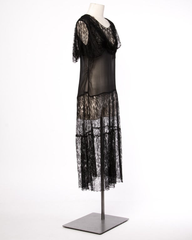 Completely sheer black silk chiffon and lace flapper dress from the late 1920s. Flutter sleeves and a draped neckline. This dress has no closure and pulls on over the head. In excellent, wearable condition.