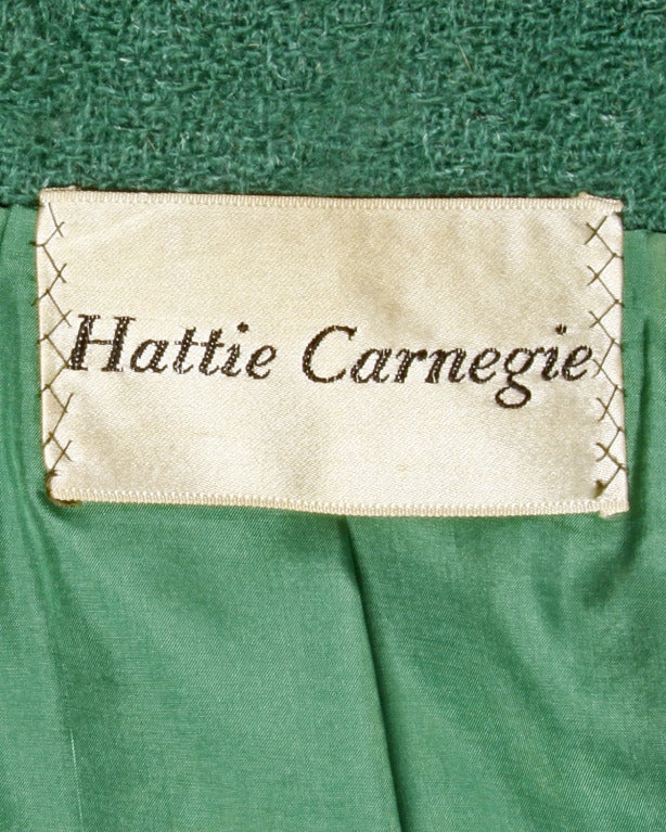 Gorgeous green wool suit by Hattie Carnegie. Unique tailoring featuring tiny slit pockets, a rounded collar and oversized heavy plastic scalloped buttons. Fully lined in creamy green silk.

DETAILS:
Jacket is fully lined with front button