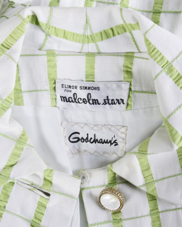 Grüner und weißer Mantel aus strukturiertem Stoff mit modischen Details und schweren Muschelknöpfen von Elinor Simmons für Malcolm Starr. Spitzer Kragen und Knopfverschluss vorne.

Einzelheiten

Vollständig
