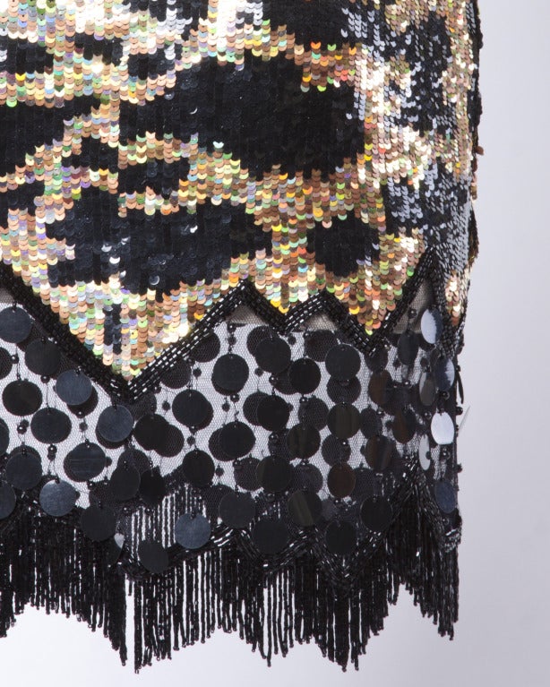 Sparkling holographic gold and black sequin and beaded mini dress by Lillie Rubin for Naeem Khan's Riazee Boutique. Black beaded fringe trim and spaghetti straps. Unworn with the original tags still attached.

Fully Lined
Back Zip and Hook