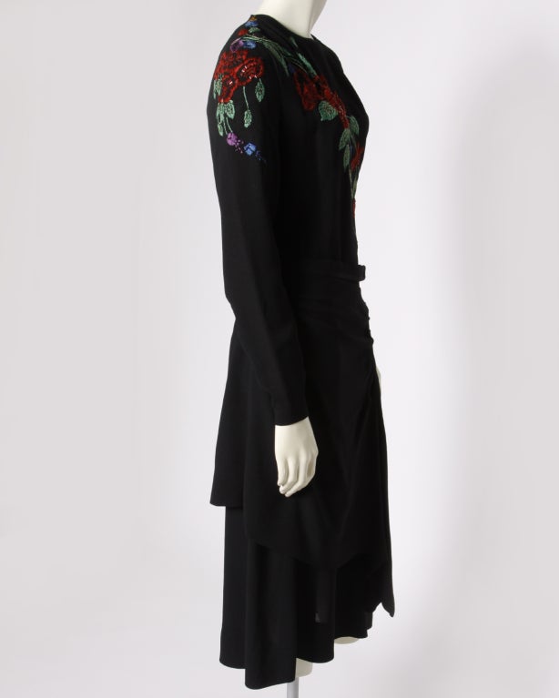 Chic black crepe 1940's dress with hand embroidered and beaded flowers across the bust and right shoulder. Lined skirt. Back and side metal zip closure. Matching waist tie included. 

DETAILS:

Circa: 1940's
Estimated Size: S-M
Color: Black /