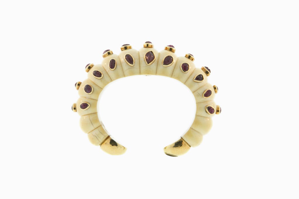 An 18kt gold, ivory and carved ruby bangle the gold mounded carved bangle with gold mounted carved ruby detail