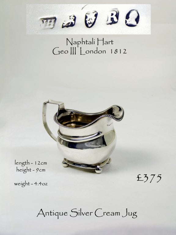 A plain Georgian rectangular silver cream jug with gadroon border and spherical feet