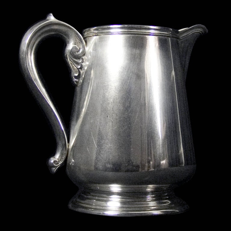 A large 20th Century American silver water or beer jug with scroll handle and thread border.