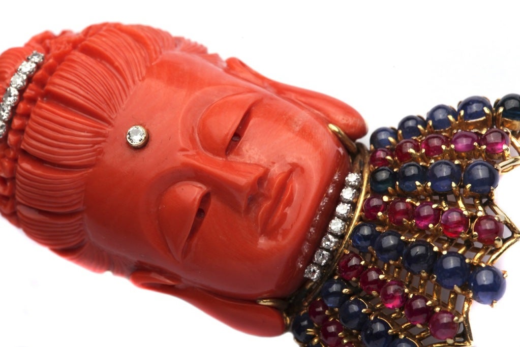 A peculiar red coral brooch, with the possibility of being transformed into a pendant, representing the upper bust of a Buddha. Other than fine quality coral, the item presents cabochon cut rubies and sapphires as well as brilliant cut diamonds, on