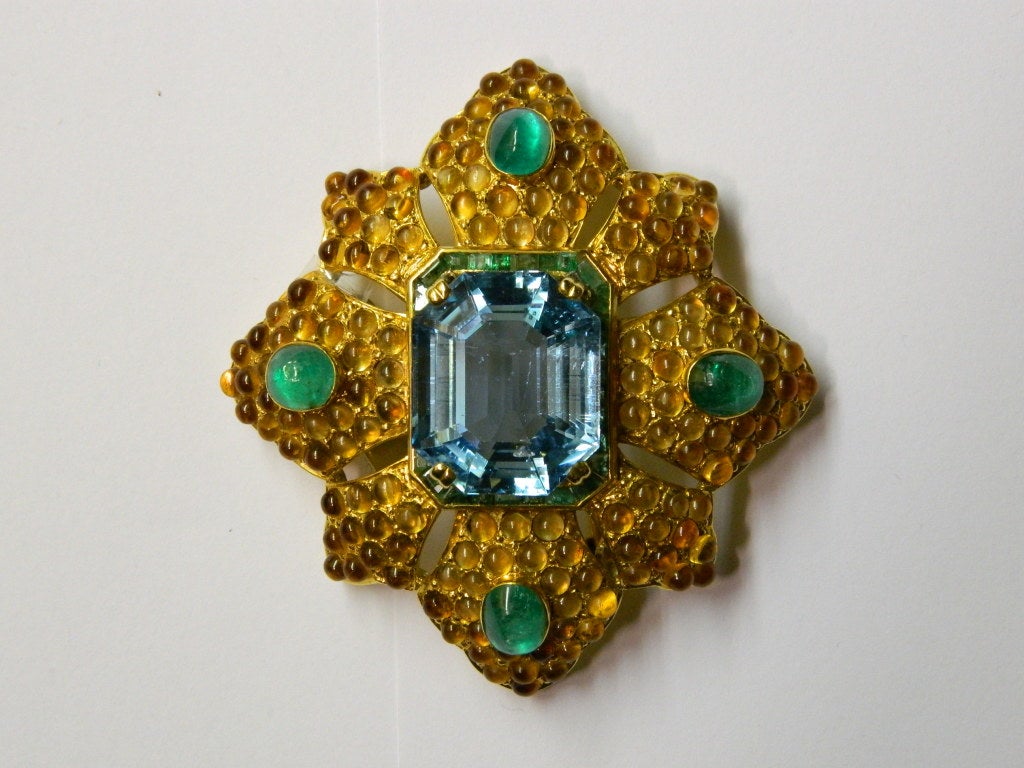 A peculiar star shaped brooch centering a very fine aquamarine weighing 35,4 cts, sided by four cabochon emeralds, embellished by a pavè of cabochon citrines, on a fine 18k yellow gold mounting. Van Cleef & Arpels, circa 1960.
