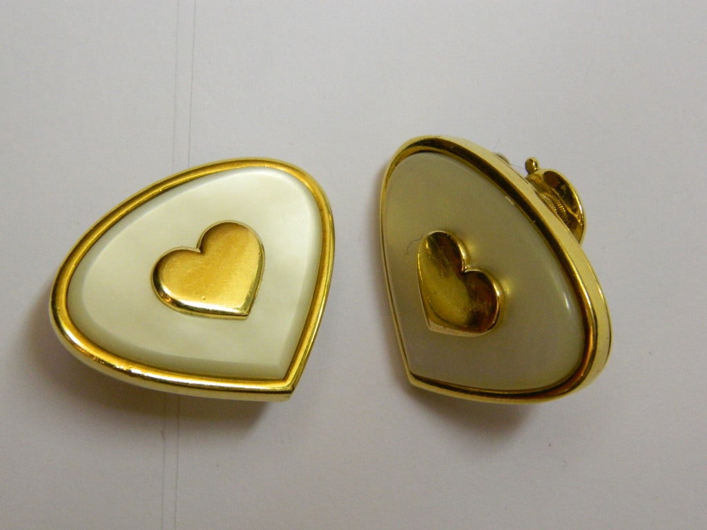 A pair of sophisticated earrings manufactured in France by Marina B during the 1980s, presenting mother of pearl decorations on an 18kt yellow gold mounting, centering a heart shaped gold element.